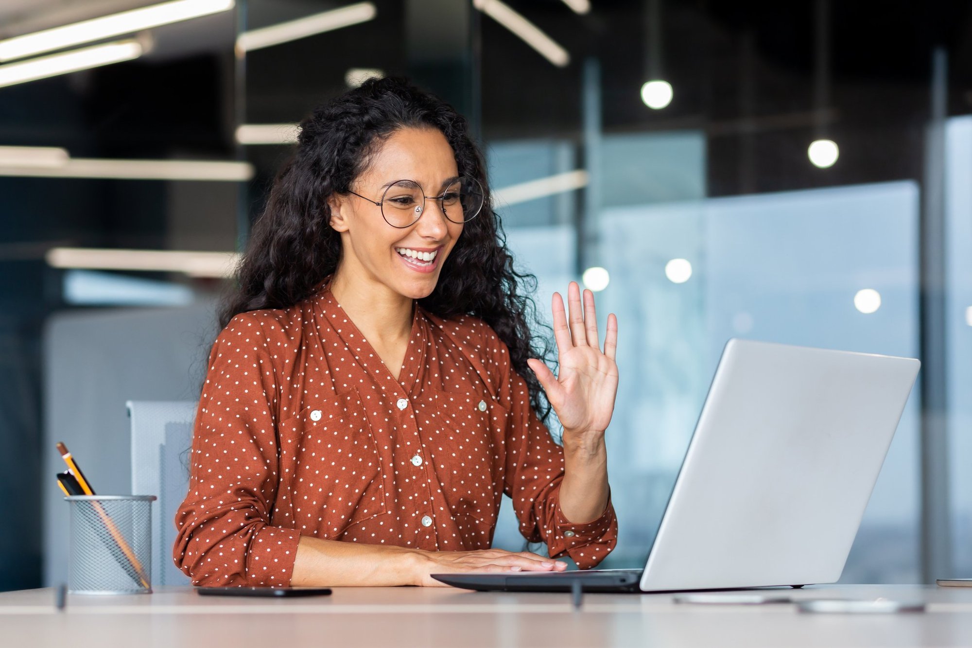 An interpreter smiles and waves to an online meeting