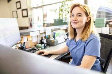 A medical worker smiles as she hangs up a phone call with an interpreter