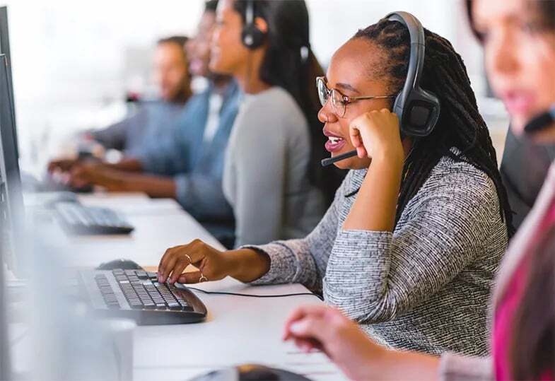 A customer Service agent speaks to a customer on the phone with the help of an interpreter