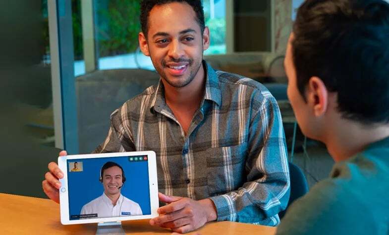 Two men have a discussion with the help of an interpreter on an ipad.