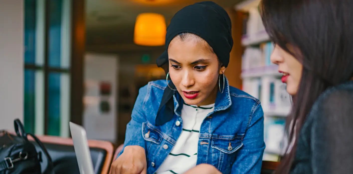 two women look at translated content on a computer.