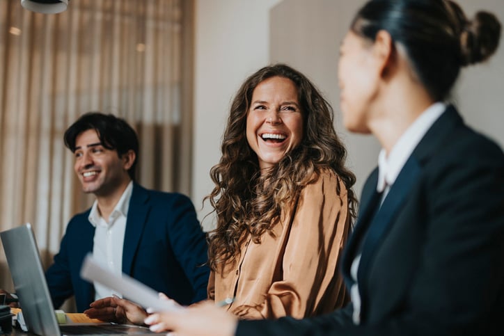 Two smiling women go over a translated document together in a meeting.