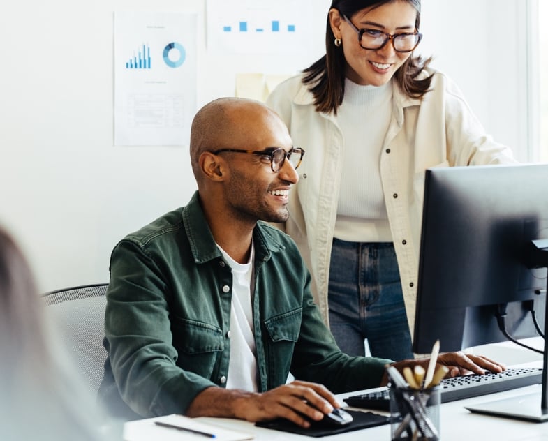 Two linguists collaborate on a content optimization project on a computer while smiling