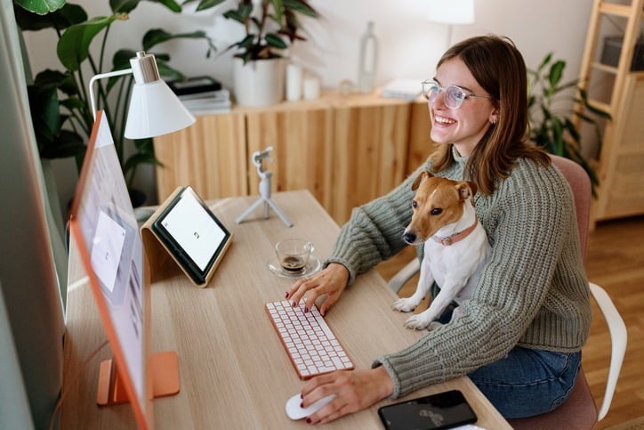 A woman in her home office with her dog enjoy the website translation automation tools for her website.