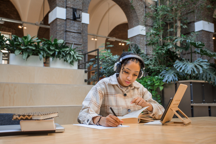 A linguist works on a translation on paper with a tablet in front of her.