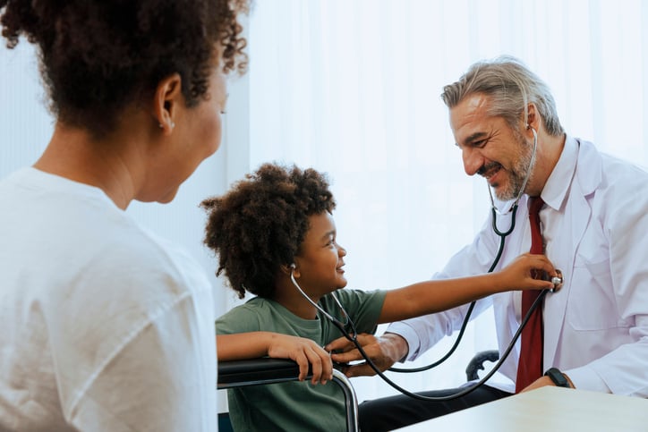 A child holds a stethescope to a doctor's chest during a healthcare appointment